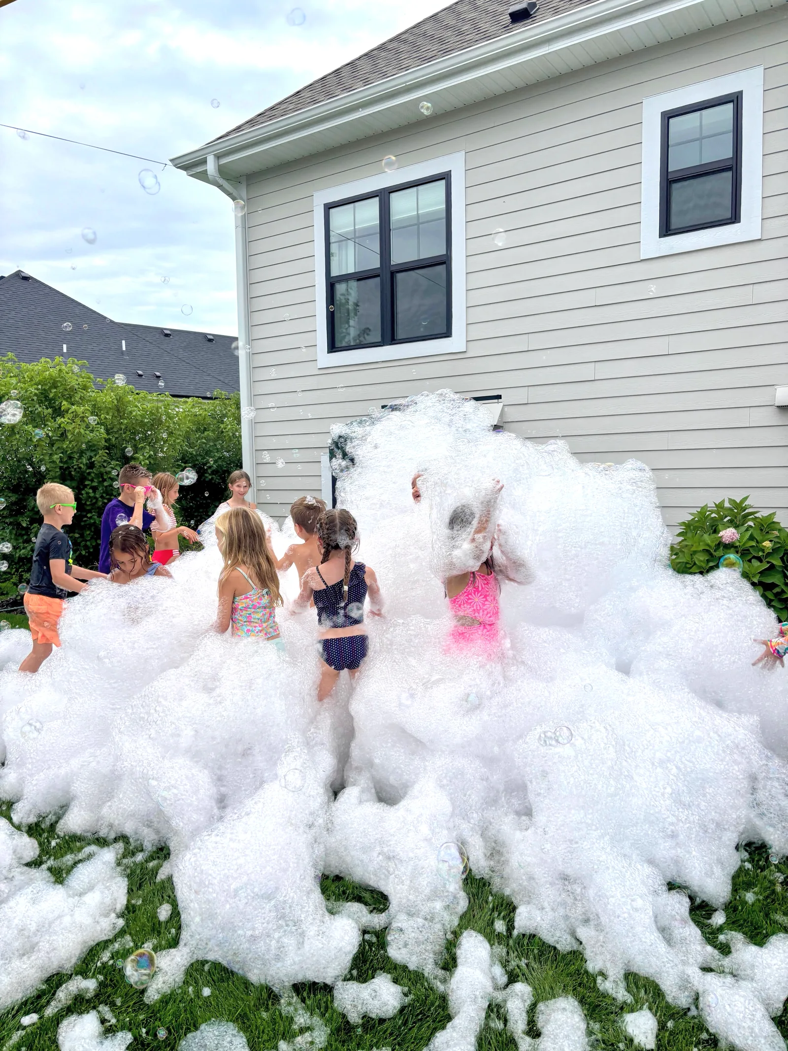 Kids playing together in piles of foam at a backyard party